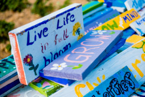 Hand-painted wooden blocks with inspirational messages like "Live Life in full bloom" and "Grow" displayed