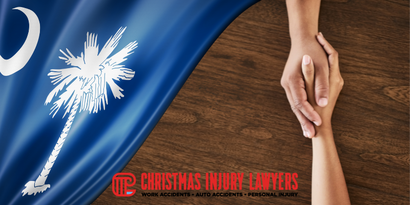 Hands reaching out in support over a South Carolina flag, with the Christmas Injury Lawyers