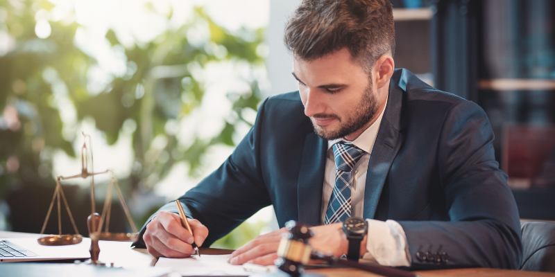 Professional male attorney in a suit writing notes at a desk, symbolizing dedicated legal representation