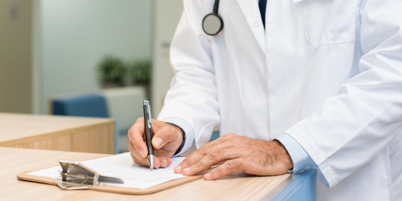 Medical professional in a white coat writing notes on a clipboard, emphasizing the importance of