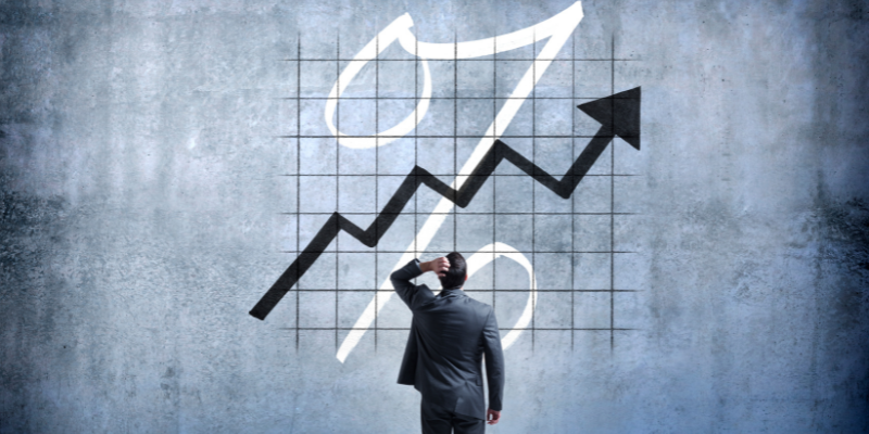 Businessman observing a rising interest rate graph, symbolizing the dangers of compounding interest on settlement