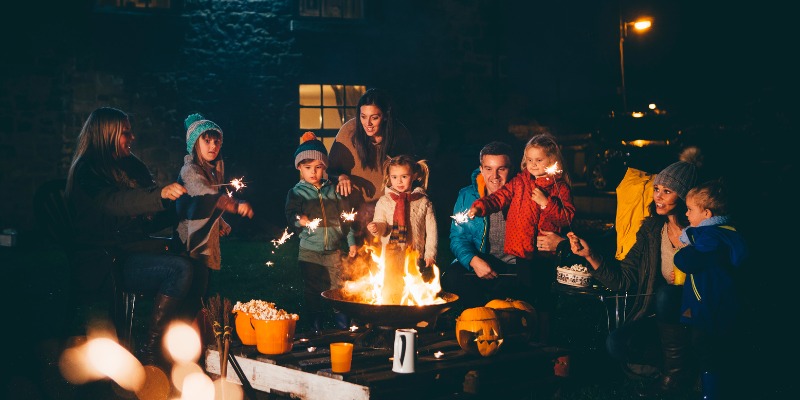 Family enjoying a festive outdoor fire with sparklers, illustrating holiday safety and accident prevention tips