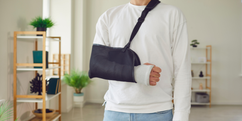 Person wearing a shoulder sling and bandage on their arm, symbolizing recovery from injuries commonly