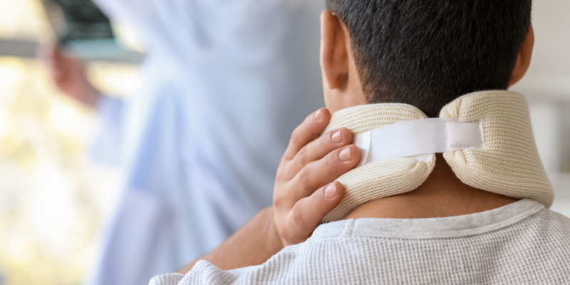 Man wearing a neck brace, indicating a severe injury, while a medical professional prepares to