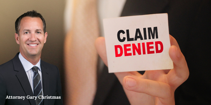 Workers compensation attorney Gary Christmas in North Charleston, SC, holds a card displaying "Claim Denied,"