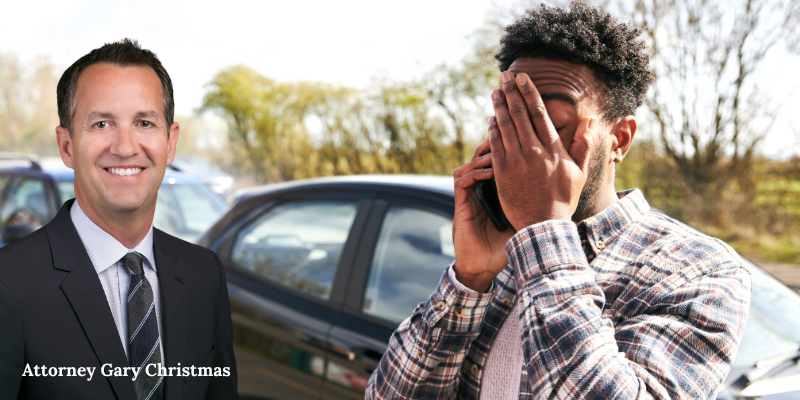 A distressed man on the phone after a car accident, with Attorney Gary Christmas standing