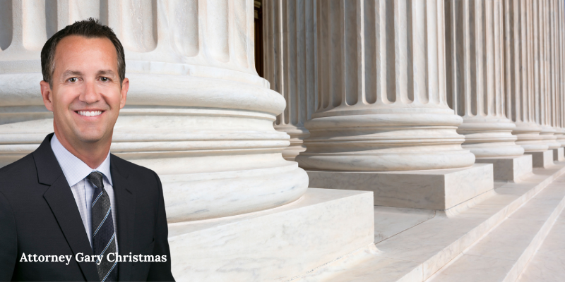 Confident attorney Gary Christmas of Christmas Injury Lawyers standing near courthouse columns, representing clients in