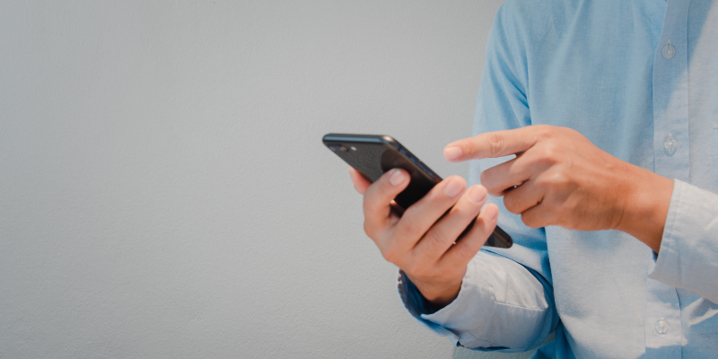 Man holding and pointing at a smartphone, illustrating a step in the workers compensation claim